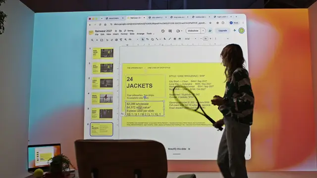 A person standing at a wall-sized screen while a slide deck assembles itself on it