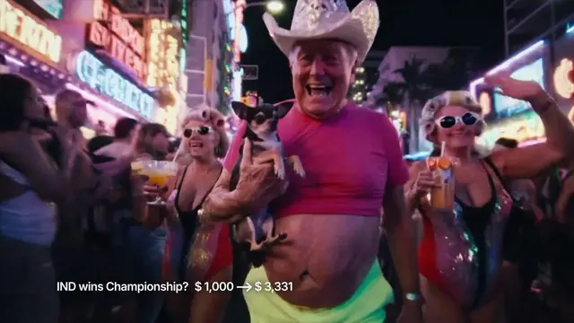 A grinning older man in a pink cropped shirt and a sequined cowboy hat holds a small trembling chihuahua on a neon-lit street at night, a frame from the AI-generated Kalshi ad